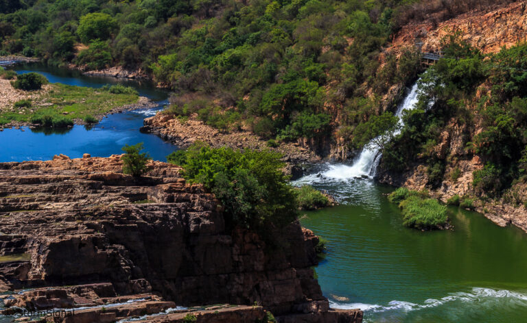 Waterfall dropping into a green pool between rocky cliffs
