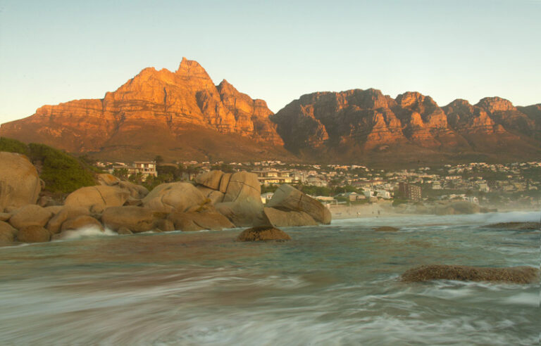 Waves washing around granite boulders at sunset