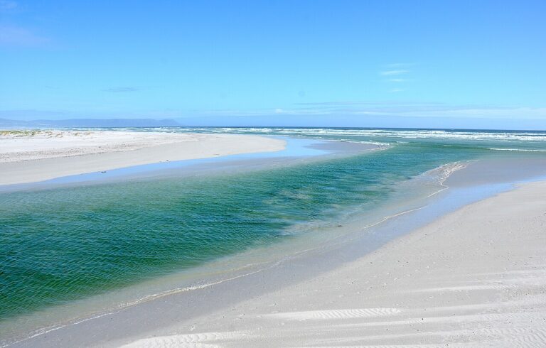 Turquoise estuary channel bordered by white sand